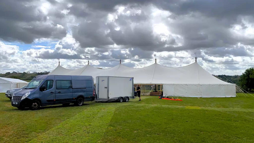 Delivery van and trailer infront of white marquee dropping off furniture